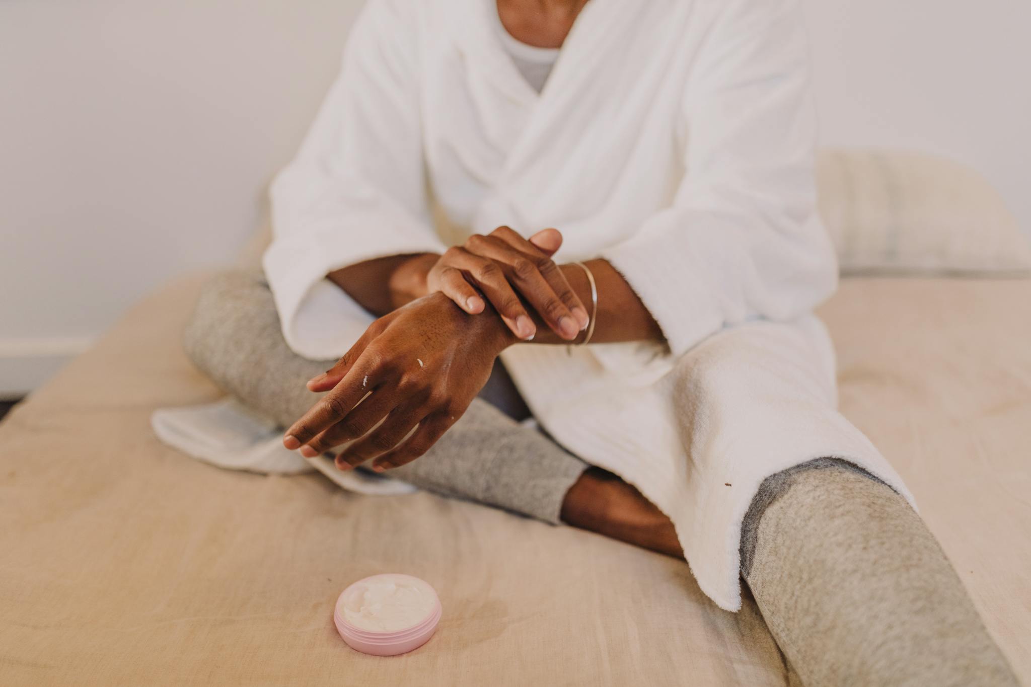 Woman applying lotion in a cozy setting, embracing self-care and relaxation.
